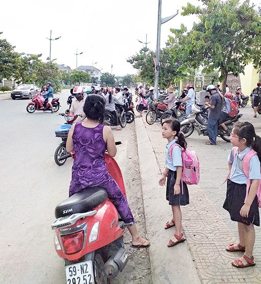 Phụ huynh đứng dưới lòng đường chờ đón con