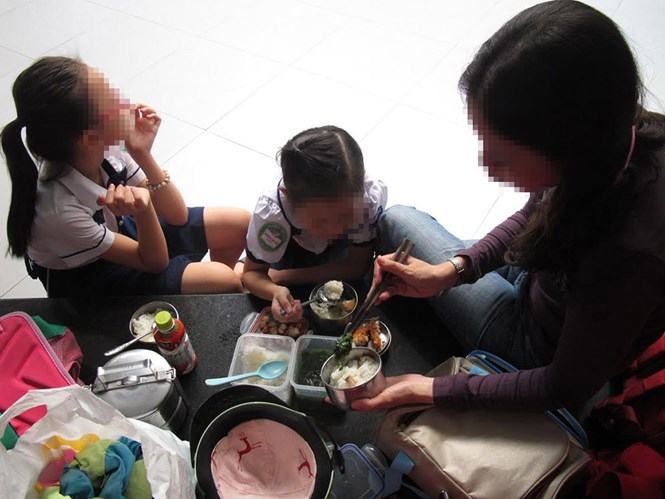 Một phụ huynh mang cơm cho con ăn ngay tại trường sau giờ học để con đi học thêm
 /// Ảnh: Đào Ngọc Thạch