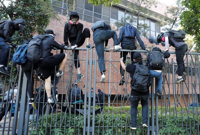 Những người biểu tình phải leo rào quay về trường sau khi vấp phải sự tấn công từ cảnh sát ở bên ngoài /// Reuters