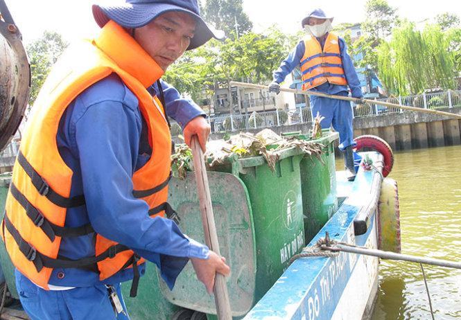 Anh Nguyễn Xuân Sơn (trái) cùng đồng nghiệp vớt rác trên kênh Nhiêu Lộc - Thị Nghè - Ảnh: K.Anh