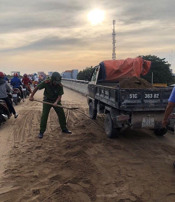 Cảnh sát giao thông - trật tự TPHCM dọn cát rơi trên đường ảnh 1