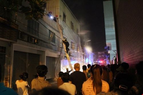 Lực lượng chức năng bắc thang tiếp cận đám cháy - Ảnh: Đức Tiến