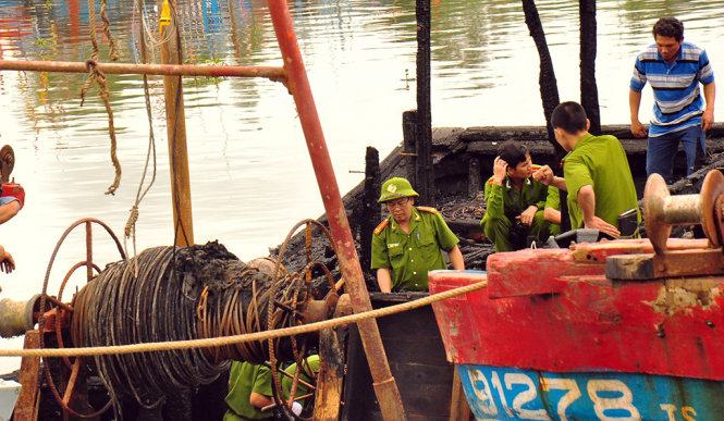 Anh Vương (áo xanh trắng) đang phối hợp cùng cơ quan công an điều tra vụ cháy - Ảnh: Trần Mai