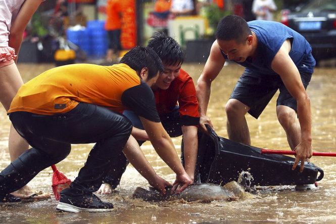 Người dân bắt cá tràn bờ khi lũ về tại thành phố Đông Hoản, tỉnh Quảng Đông - Ảnh: Reuters