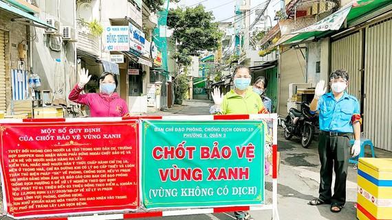 Nhân dân tự nguyện tham gia trực chốt tự quản bảo vệ  “vùng xanh” ở quận 3. Ảnh: VĂN MINH