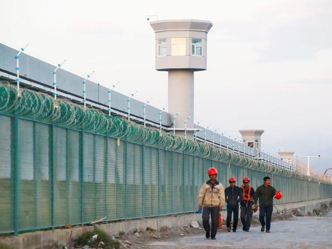 Công nhân đi bộ bên ngoài một trung tâm đào tạo nghề ở Tân Cương /// REUTERS