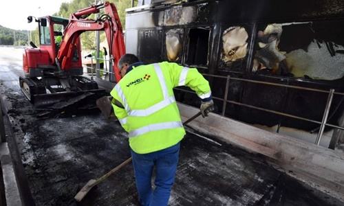 Công nhân công ty Vinci Autoroutes dọn dẹp đống đổ nát tại một trạm thu phí bị người biểu tình đốt phá. Ảnh: AFP.