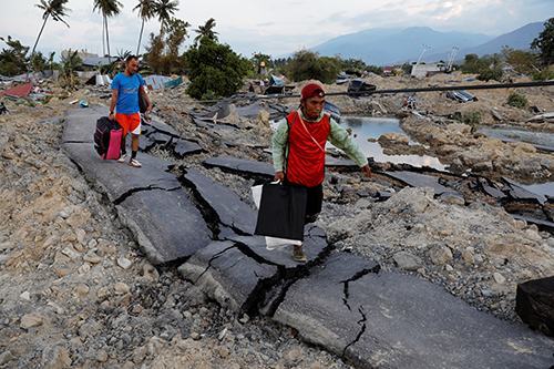 Người dân xách đồ đạc rời khỏi vùng thiên tai ở Palu, Indonesia, hôm 1/10. Ảnh: Reuters