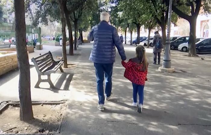 Một bé gái đi dạo cùng ông dọc theo một hàng cây ở Rome, Italy, hôm 5/3 sau khi chính phủ đóng cửa tất cả các trường học để hỗ trợ cuộc chiến chống Covid-19. Ảnh: AP