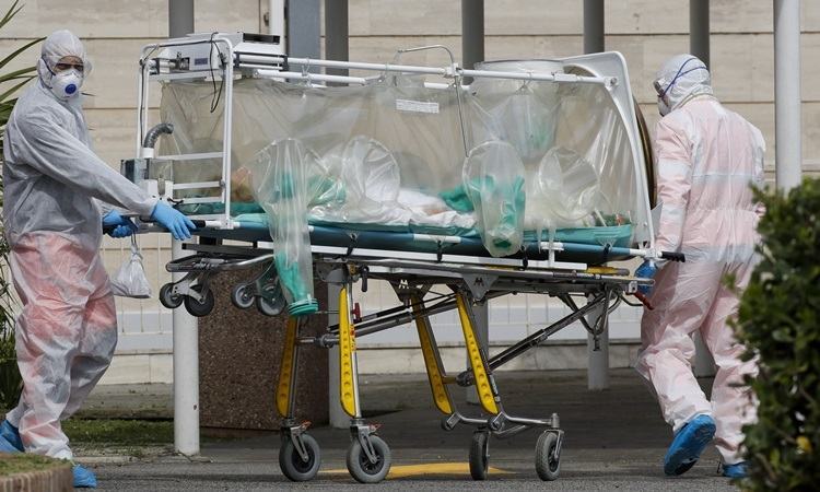 Nhân viên y tế đưa bệnh nhân nhiễm nCoV từ xe cứu thương lên cáng tại Bệnh viện Columbus Covid 2 ở Rome hôm 19/3. Ảnh: AP.