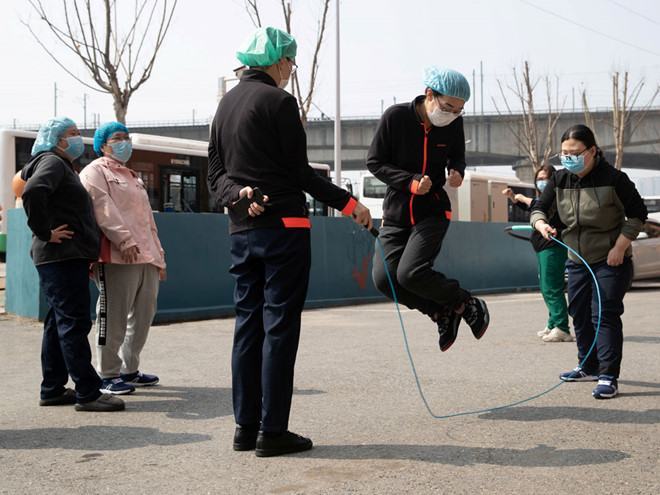 Nhóm nhân viên y tế chơi đùa bên ngoài một khách sạn họ lưu trú ở Vũ Hán ngày 5.3 /// Reuters